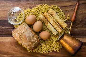 Bakery ingredients - bread, eggs, wafer rolls, Cezve, pasta on wood table. Sweet pastry baking concept. Flat lay, copy space, top view.