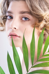 Beautiful young woman with perfect skin and natural make up. Teen model with green leaves. SPA and skincare.