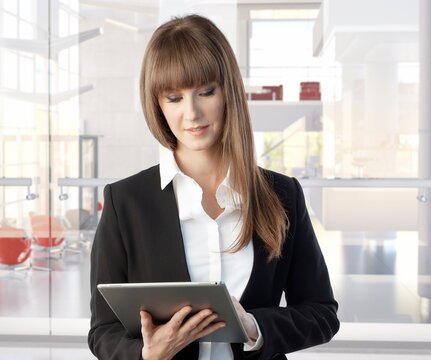 Happy white young businesswoman working with large business tablet. Woman in business office.