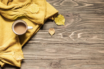 Autumn cozy composition. Cup of coffee, warm sweater, dried leaves on a wooden background. Flat lay, copy space, 