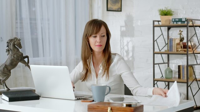 Young business woman working at desk with laptop computer in home office.