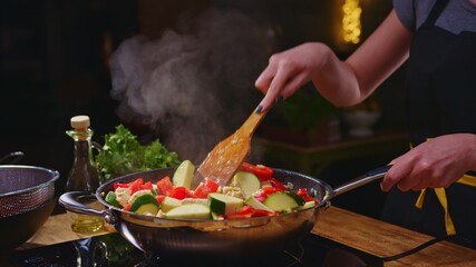 Woman cooking frying in wok pan on kitchen table.  