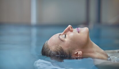 Naklejka premium Wellness - happy white woman in her 30s relaxing in wellness resort pool, smiling.