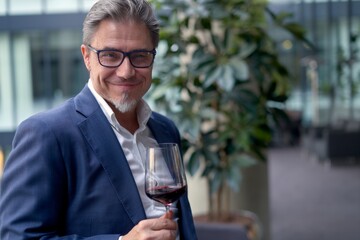Elegant older white man drinking red wine from glass on a wine tasting event. 