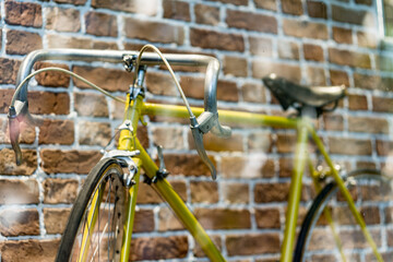 Fototapeta na wymiar Retro yellow bicycle on roadside with vintage brick wall background