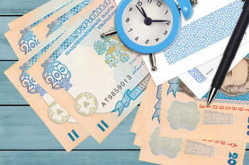 200 Ukrainian hryvnias bills and alarm clock with pen and envelopes. Tax season concept, payment deadline for credit or loan. Financial operations using postal service