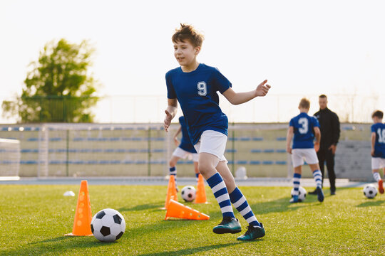 Boys running after ball on soccer training unit. Children having fun on football practice session. School physical education class on summer day