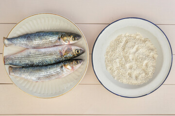 Fresh sea fish pelengas ready for frying and a plate of flour.