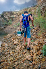 Teen boy walking with fishing equiment including pole and tackle box on rocks at lake,pole,fishing pole
