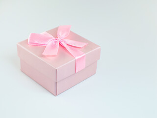 Pink gift wrapped present with rosy satin ribbon bow isolated on white