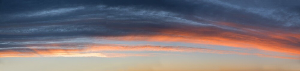 Fototapeta na wymiar wide sky panorama with gray and orange clouds, above blue sky