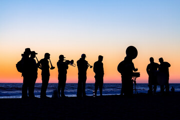 Banda en la playa de Mazatlán en un atardecer.