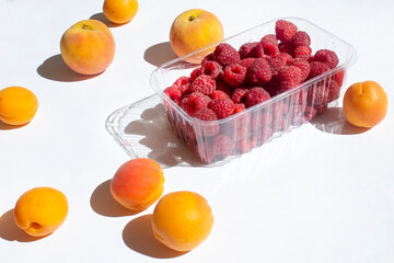 Orange apricot fruit with raspberry box on white background  fitness vitamin food concept