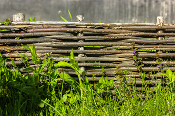 Handmade wooden wicker fence in Ukrainian style, green grass