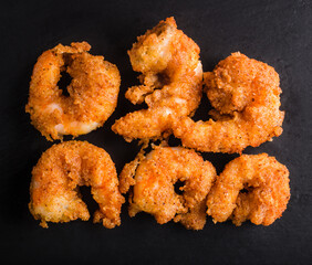 Shrimps in batter on black stone background