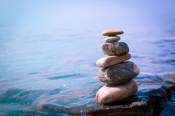 Fototapeta na wymiar Modern balance minimalism. Pebble geometric rock art. Organic balancing stones in blue water. 