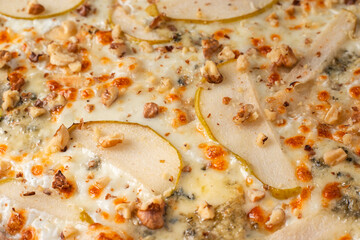 Spicy pizza with pear, nut and dorblu cheese. Macro photo . Selective focus