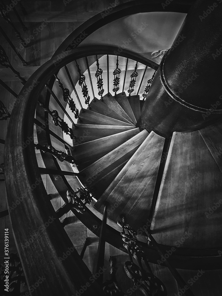 Wall mural a look down to an old spiral staircase. wooden circular stairway with ornate metallic railing, black