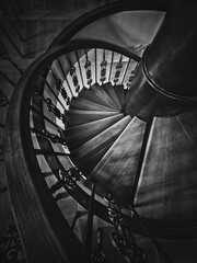 A look down to an old spiral staircase. Wooden circular stairway with ornate metallic railing,...