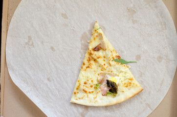 One slice of pizza in a large cardboard box. The last slice of pizza with herbs and bacon.