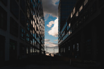 Obraz premium Silhouette person standing between two big modern buildings with glass reflecting the sky