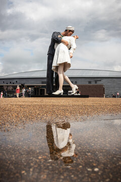 A statue of a sailor kissing a girl located in Portsmouth dockyard, replicating the famous photo taken in time square at the end of world war two reflecting in a puddle