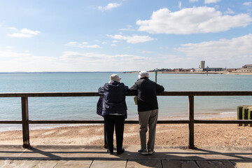 Obraz premium an elderly couple leaning on a fence looking at a view by the sea