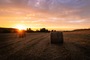 sunset over a field of hay bales 