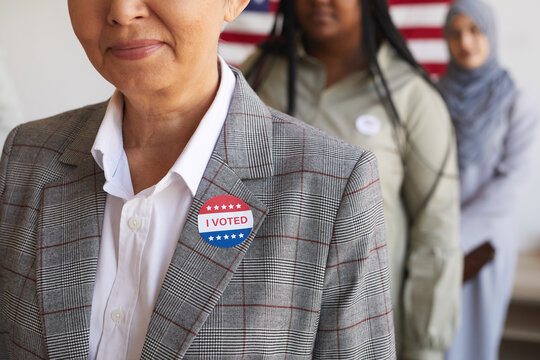 Cropped image of multi-ethnic group of people at polling station on election day, focus on smiling senior woman with I VOTED sticker in foreground, copy space
