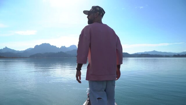 A young guy in a pink hoodie a traveler on a long tailed boat goes to the island lake Cheo LAN and travels concept with an adventure girl and with a guy a tourist wanderer on an excursion to Thailand