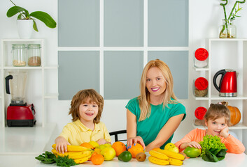 Young mother and her two children eating fruits and drinking smoothie, mothers day concept, Healthy food at home.