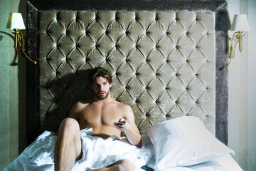 Carefree guy enjoying morning. Shirtless man in bedroom. Handsome man in underwear sitting on bed.