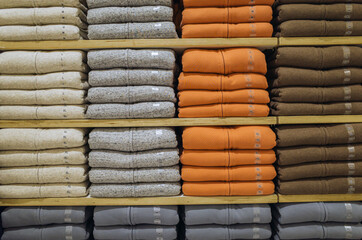 Various vibrant color shirts perfectly folded on a shelf in the shop.