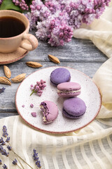 Obraz na płótnie Canvas Purple macarons or macaroons cakes with cup of coffee on a gray wooden background. Side view.