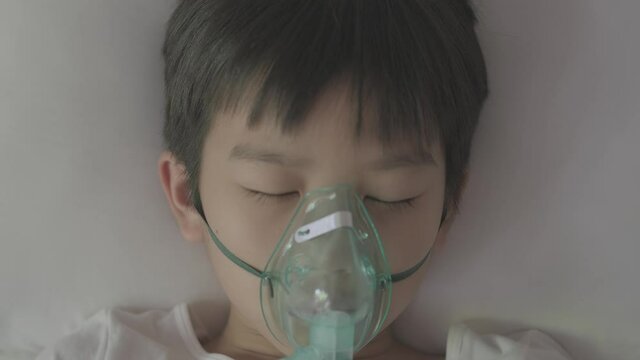 4k Top view Young asian boy with oxygen mask sleep on a bed