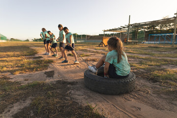Group of kids pulling a girl sitting on a tire at a boot camp