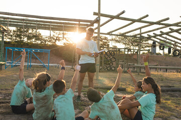 Male fitness coach giving instructions to the kids at a bootcamp