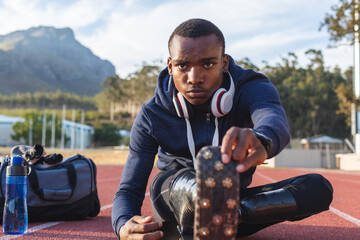 Black African American Male athlete with prosthetic leg performing stretching exercise