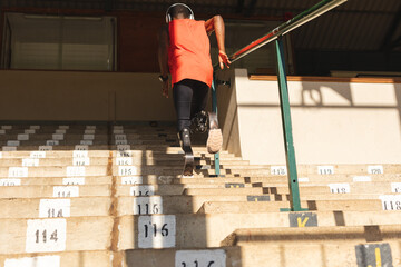 Rear view of Black African American male athlete with prosthetic leg running up the stairs