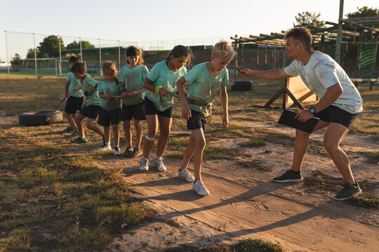 Group of kids pulling a rope tied to a tire at a boot camp