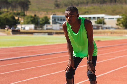 Black African American Male athlete with prosthetic leg taking a break from running