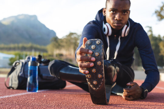 Black African American Male athlete with prosthetic leg performing stretching exercise