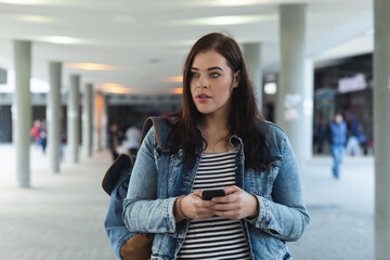 Curvy Caucasian woman using her smartphone in the city streets