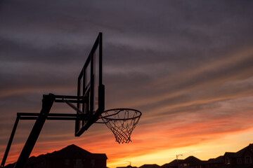 Basketball backboard and  hoop rim silhouette with sunset in the background