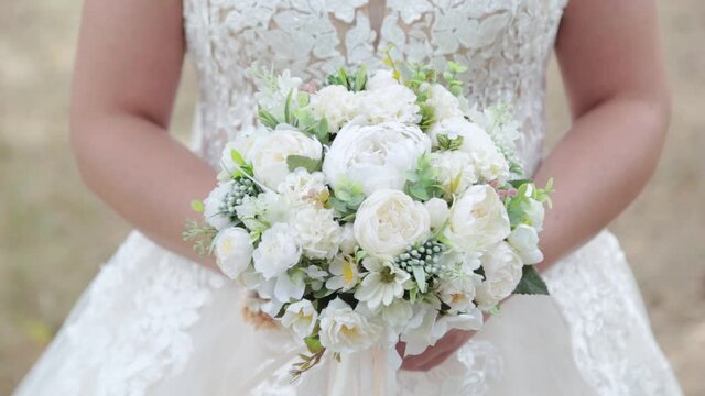 Bride with wedding bouquet in green summer forest.