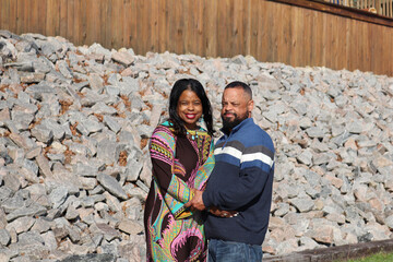 Fototapeta na wymiar Loving African American couple holding hands by rocks and fence