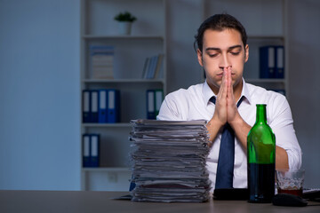 Alcohol addicted businessman working late in the office