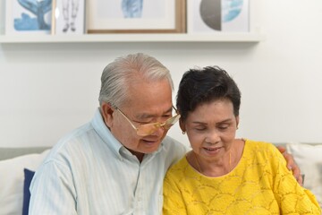 grandfather and grandmother used laptop to see photo or shopping on line in living room.Senior family concept.