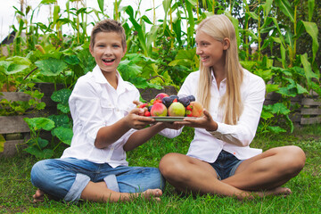 Boys and girls fall and summer eating vegetables and fruits in nature in white shirt
