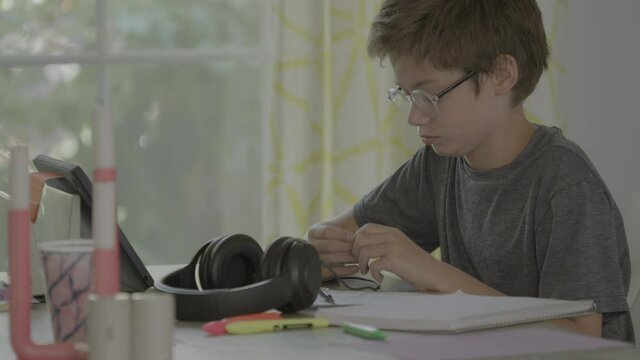 A restless boy at home in a virtual class on his iPad fidgets.